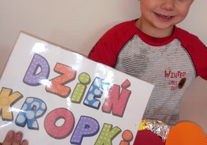 Chłopiec trzyma ramkę i napis Dzień Kropki